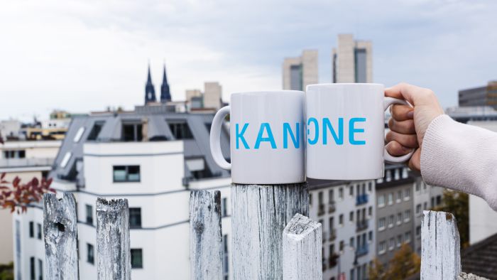 Zwei KAN-ONE Tassen vor dem Kölner Dom im Hintergrund